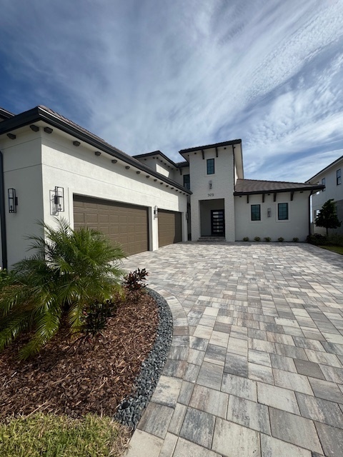 a modern house with a custom paverstone driveway, and brown garage doors