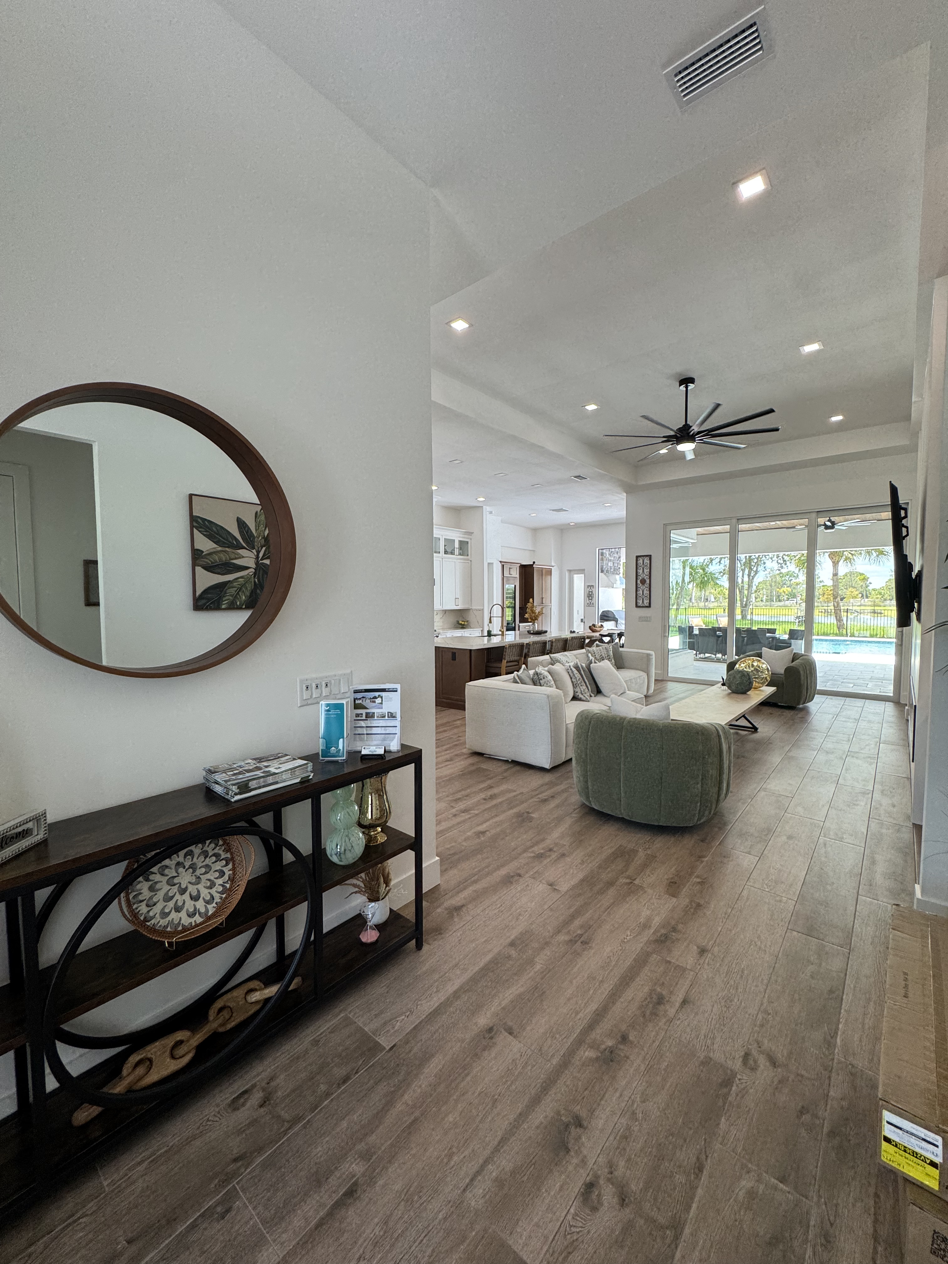 entryway looking into living room with a circular mirror and side table against the wall