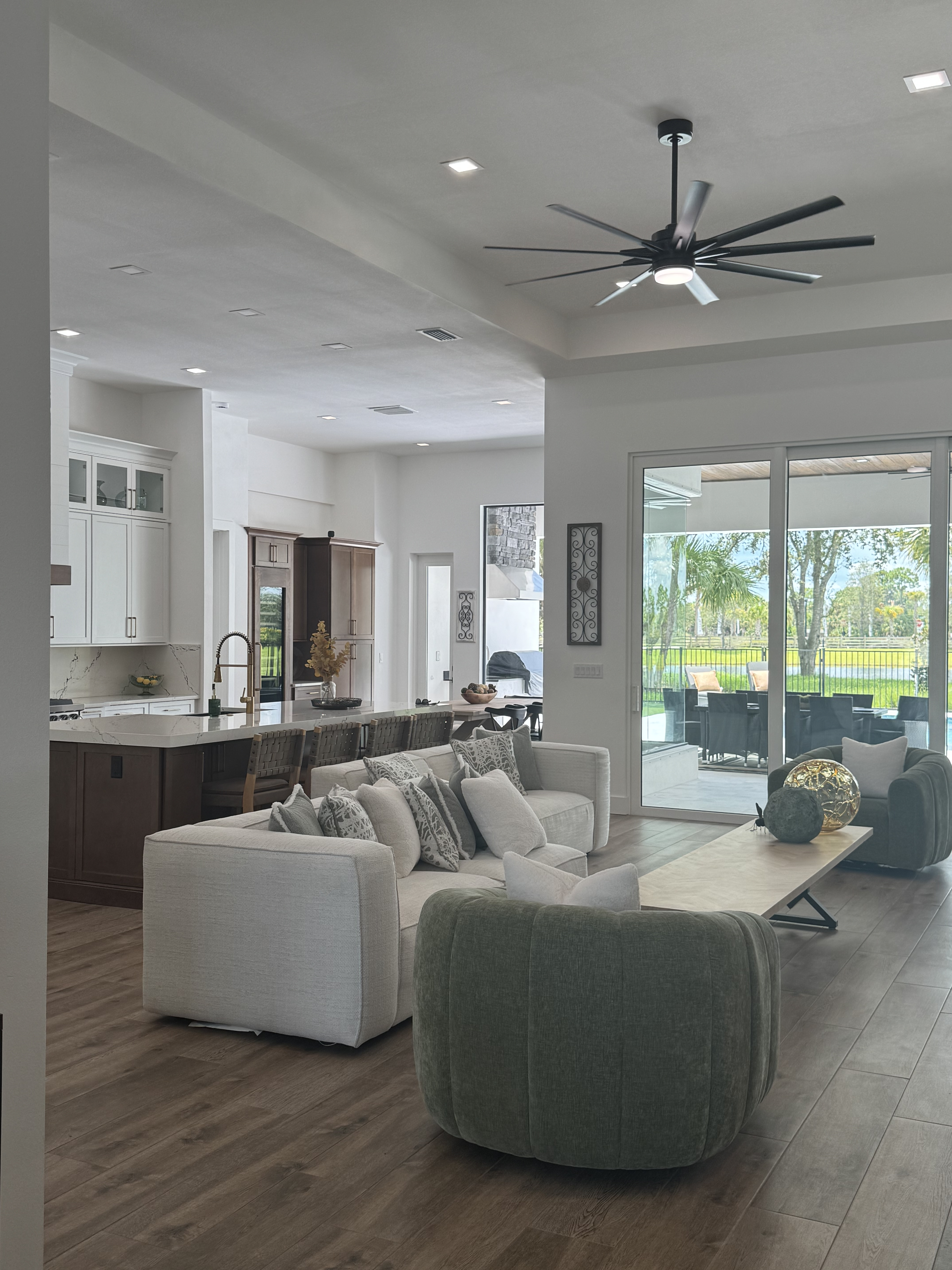 a living room with wood floors, two white love seats and two olive green sitting chairs