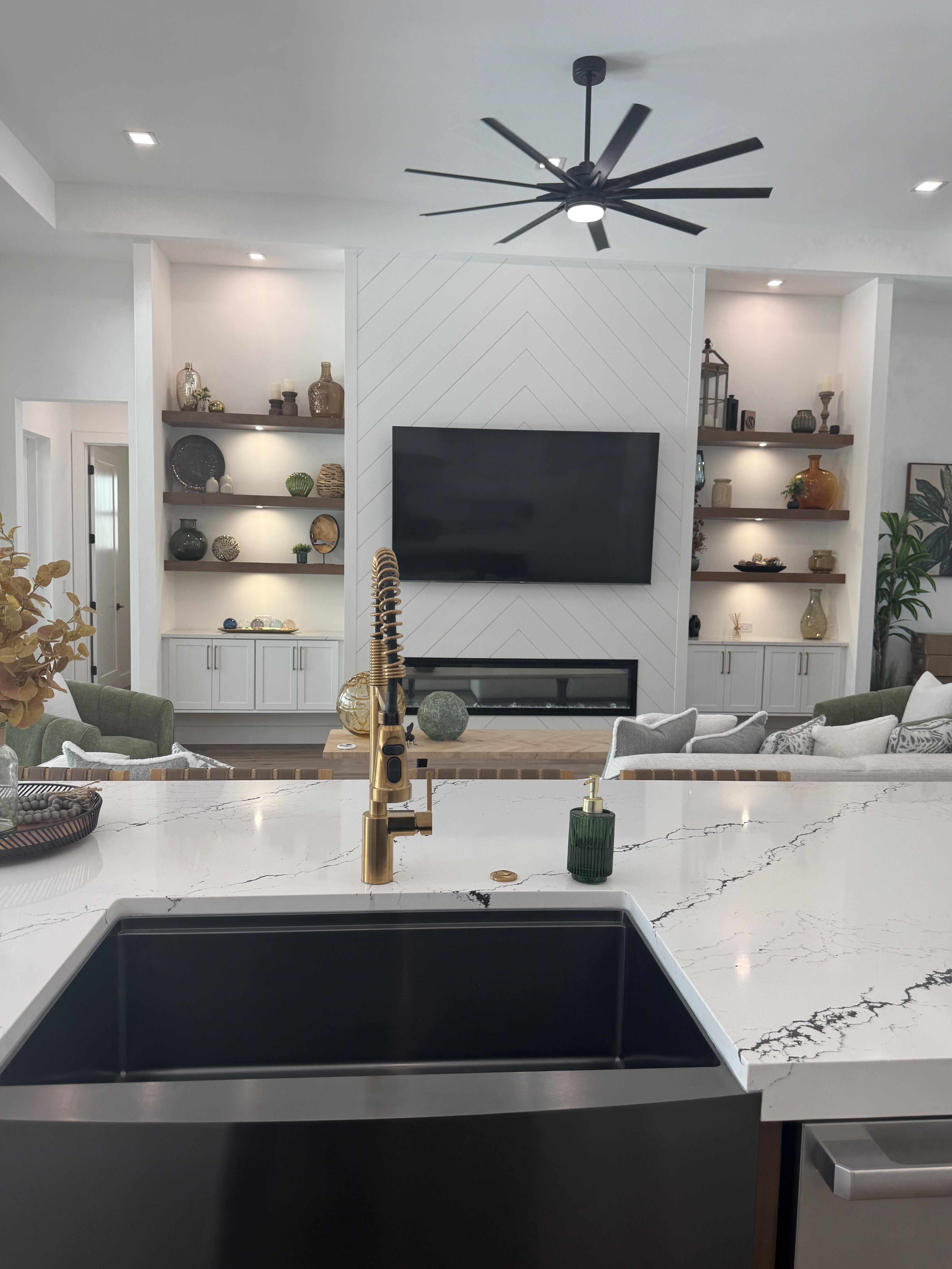 view of a living room from behind a kitchen island with marble countertops and a tv hanging on the wall