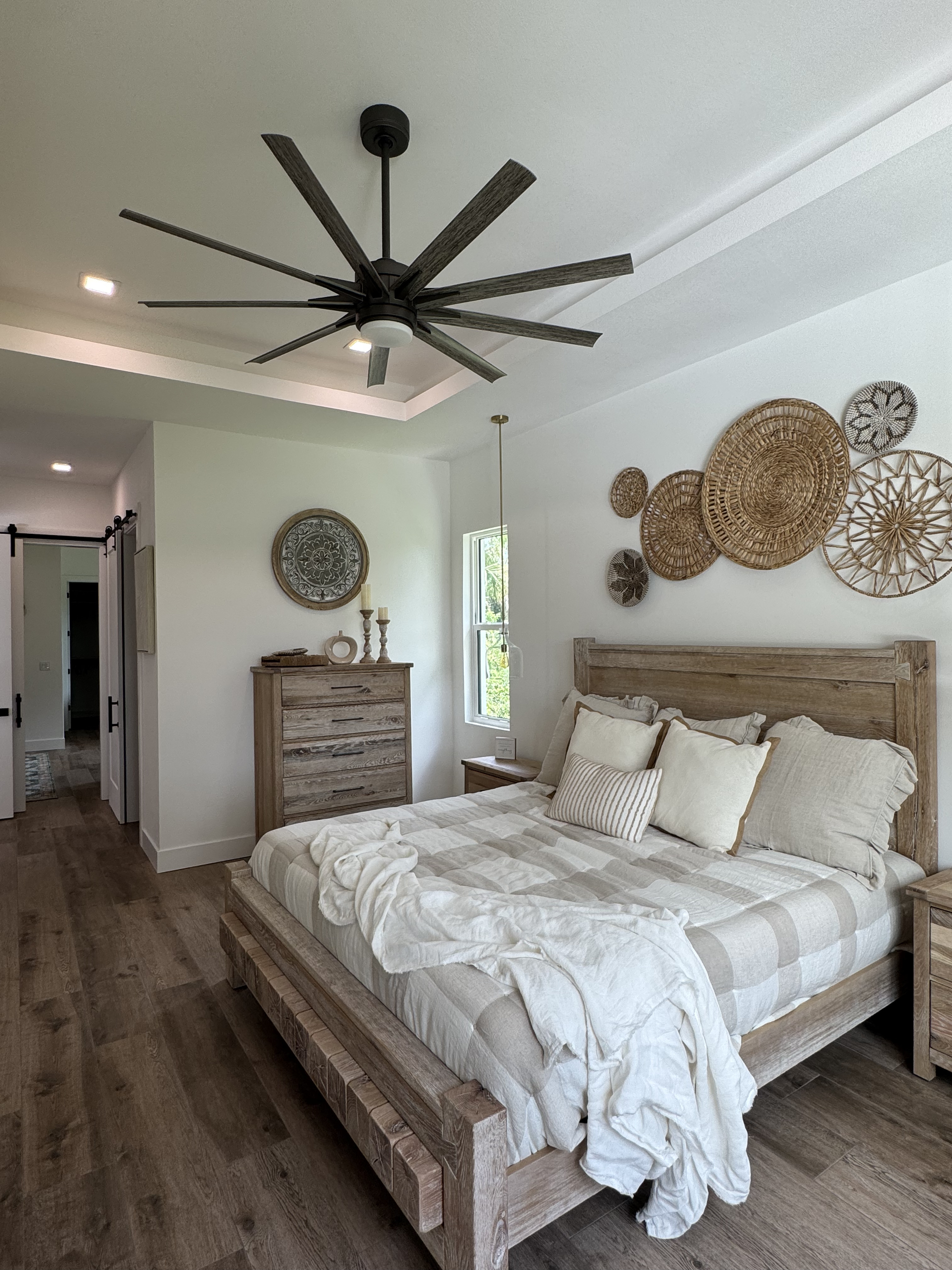 a master bedroom with wood floors and wooden furniture with a modern ceiling fan