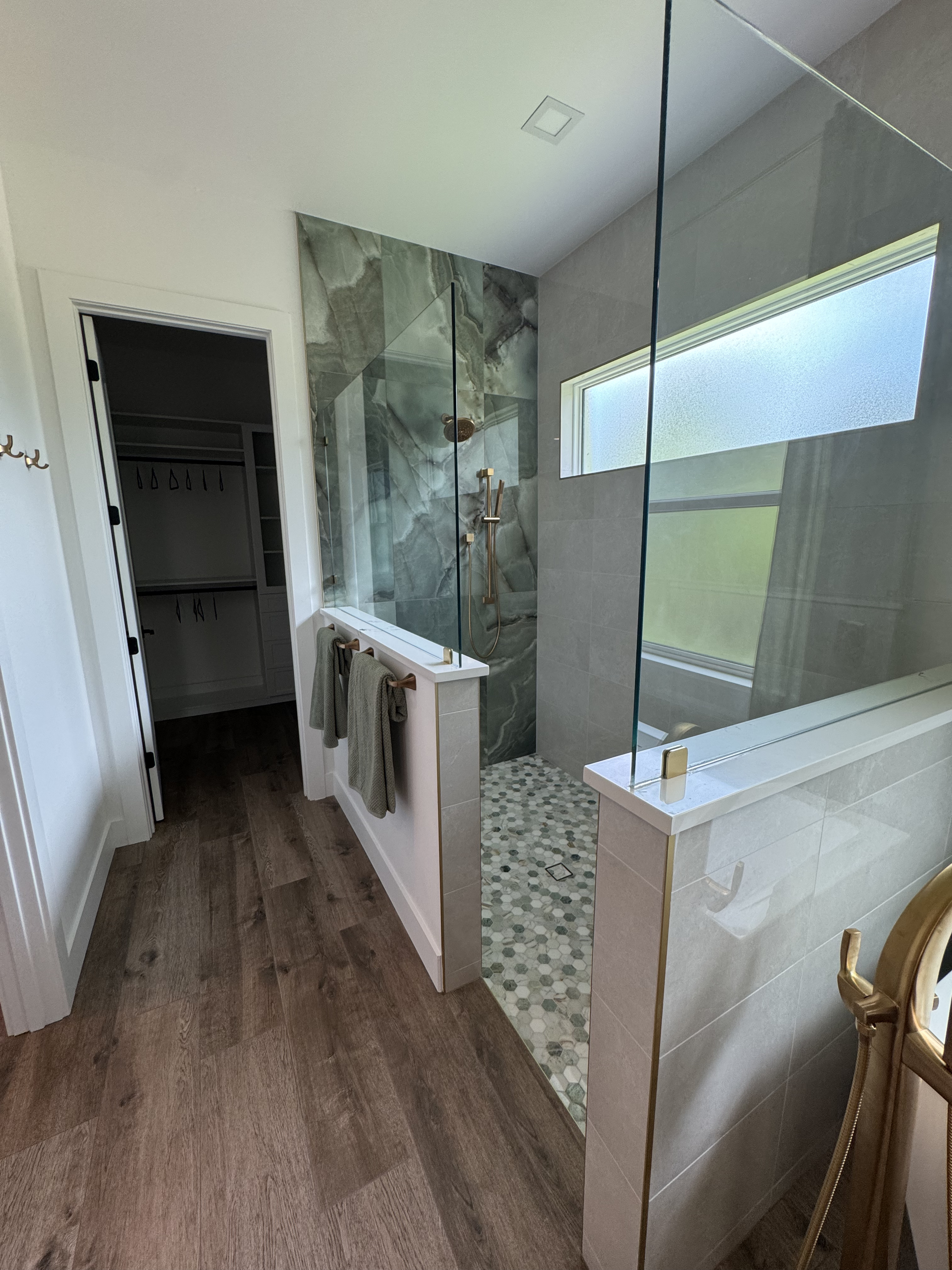 a shower with jade marble tile and three quarter glass walls