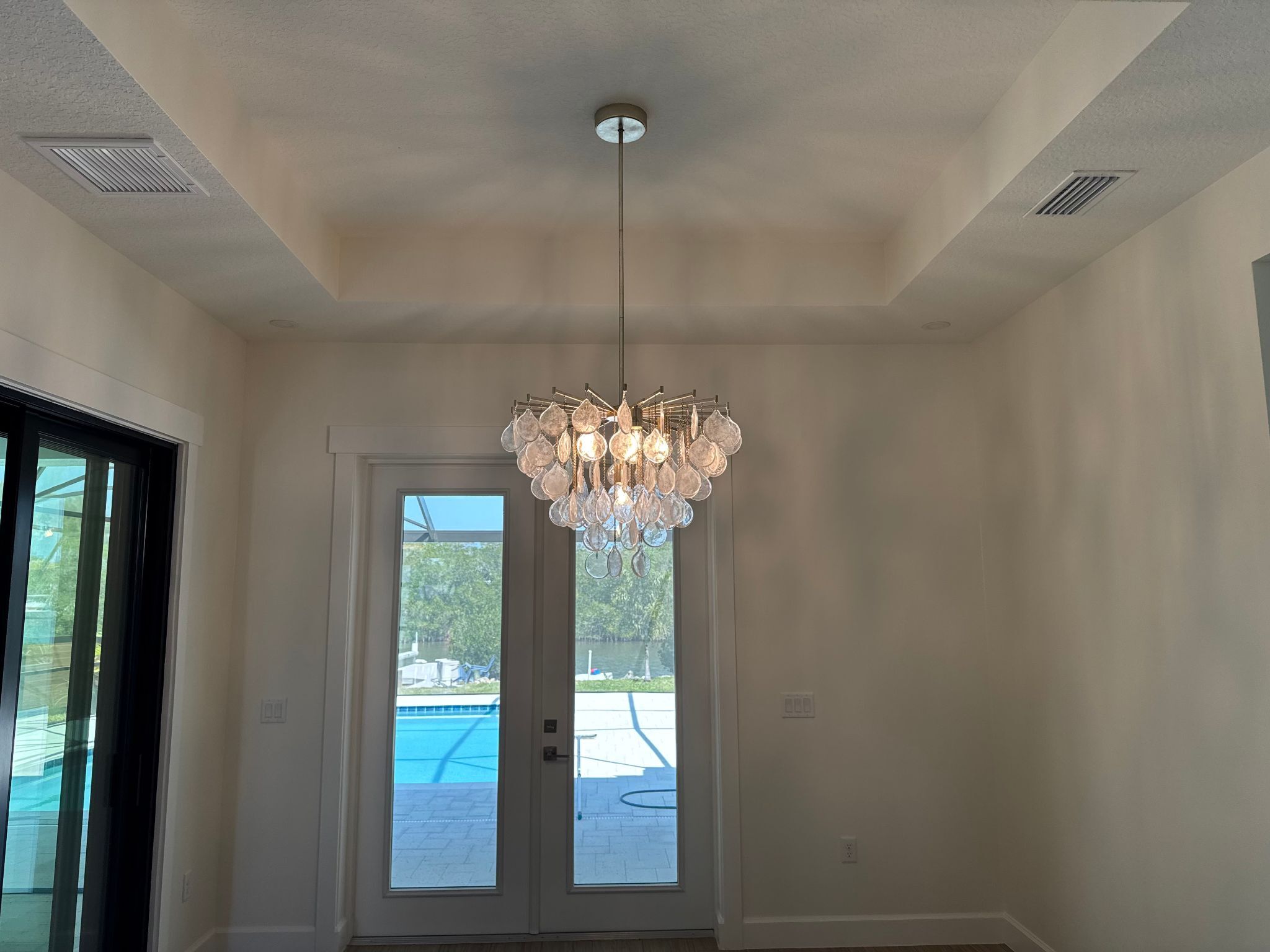 chandelier hanging in entryway of home with hanging glass flat teardrop shapes