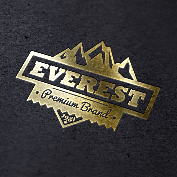 3columnbanner.jpg a close up of a gold foiled everest logo on black paper