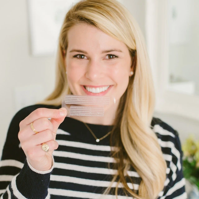 Woman holding a Crest 3D Whitestrips strip