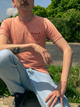 Front of Eat The Rich tee on male model, showing front pocket design of cat head