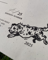 image of an illustration mark at the bottom of a certificate of authenticity. Mark is an illustration of Skips' the dog and his 3 legs jumping. Under illustration is "2025". This portion of the certificate is custom in-house formulated raised gloss spot thermography.  above illustration is a portion of the signing and edition numbering