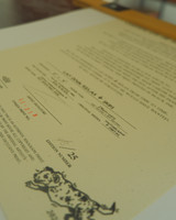 low angle photograph of the signing of the certificate of authenticity and artist statement. text on document is blurry and illegible in photo.
