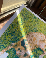 Image of the art print product being held near a window with a sunbeam coming across the print in a diagonal from top left to bottom right. Sunbeam highlights how light changes the appearance of the art.