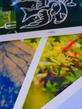 Cropped image of several art prints. Image is featuring many bright colors and grainy textures. Prints are stacked in a loose pile. None of the prints show any identifiable image. Image serves as an inspiration/ reference to maybe the type of print you may receive.