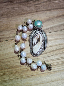 2 inch carved bone horse head pendant
3.25 inch sterling silver setting with engraved back and feather accents, large turquoise stone on connector
16 inch chain with large simulated pearls 2 inch carved bone horse head pendant
3.25 inch sterling silver setting with engraved back and feather accents, large turquoise stone on connector
16 inch chain with large simulated pearls
