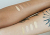 Two different arms held together with sample swatches of vegan zero-waste concealer on them in different shades