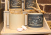 Open bamboo jar with label "Eco Clean Tabs" in lemon scent with kraft paper packaging sticking out of open jar and cleaning tablets in front on shelf display