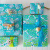 Multiple gifts wrapped in compostable and reversible light blue monstera wrapping paper