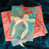 Multiple gifts wrapped in compostable and reversible coral and teal underwater flora wrapping paper