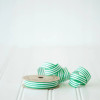 A cardboard spool of green and white striped 100% cotton curling ribbon