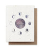 A plantable birthday card embedded with herb seeds and a purple watercolor design of moon phases saying "wishing you many more moons" with a kraft envelope