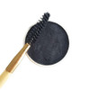 A bamboo spoolie or mascara brush dipping into an open paper pot of Zero-Waste Vegan Mascara