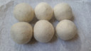 Six wool dryer balls in natural cream on a white marble counter