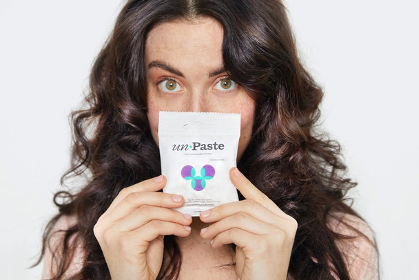 A woman holding Plastic-Free Toothpaste Bits packet