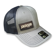 black mesh trucker hat with olive front and bill with dark brown jackson kayak leather patch logo, front black mesh trucker hat with olive front and bill with dark brown jackson kayak leather patch logo, front
