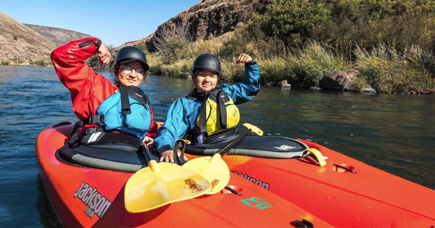 young women flexing in their Jackson Kayaks on the river