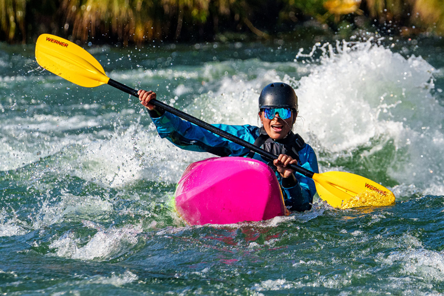 young paddler blasting through whitewater in a jackson kayak with their werner paddle