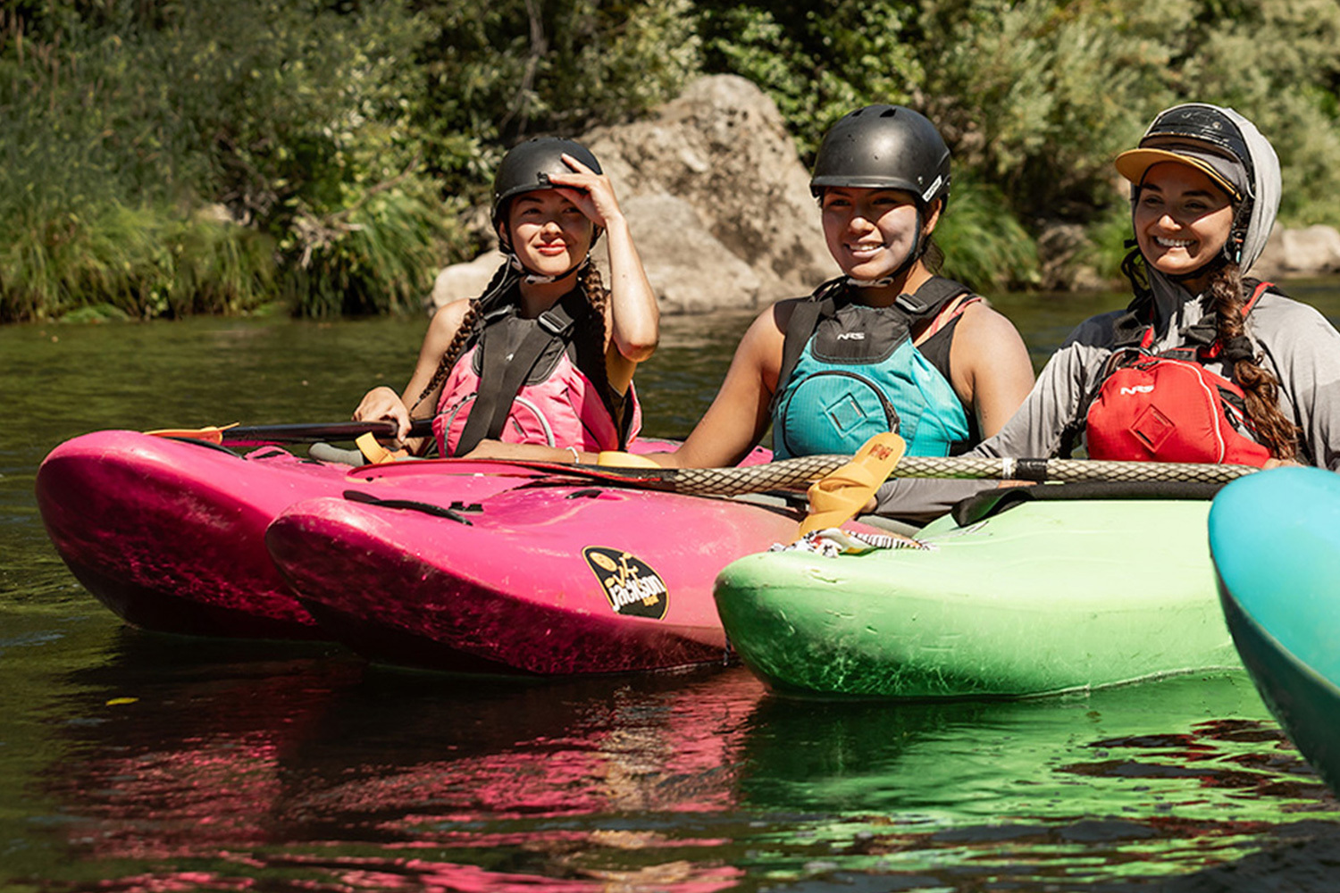 young paddler smiling while paddling their jackson kayak through whitewater