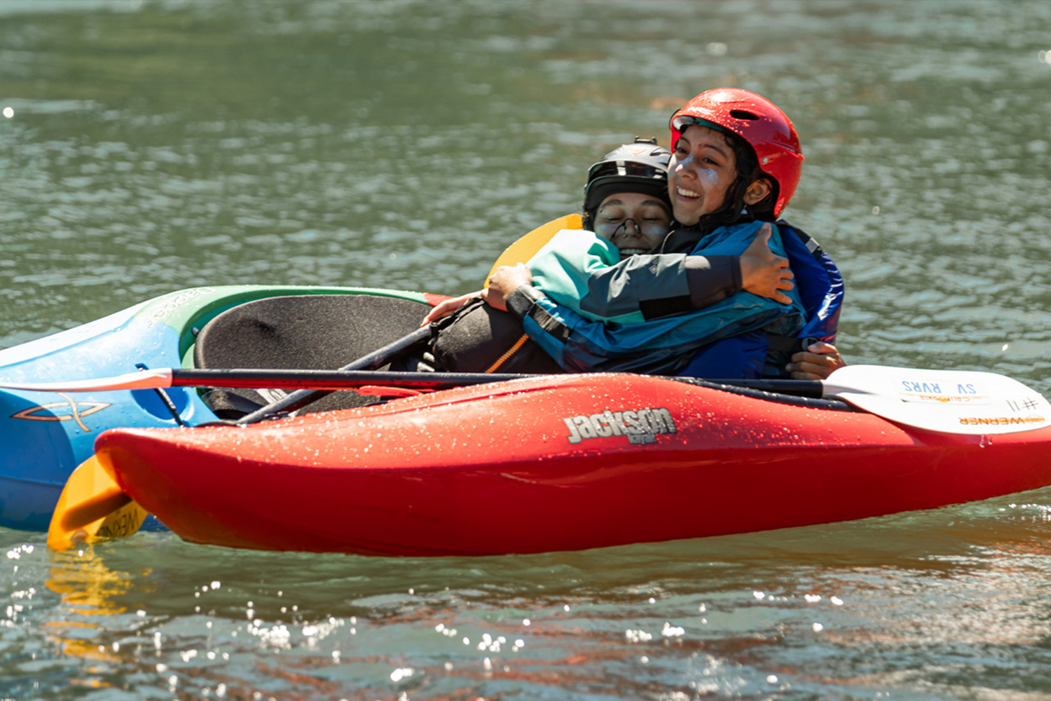 happy youth piled onto a Jackson Kayak on a river bank