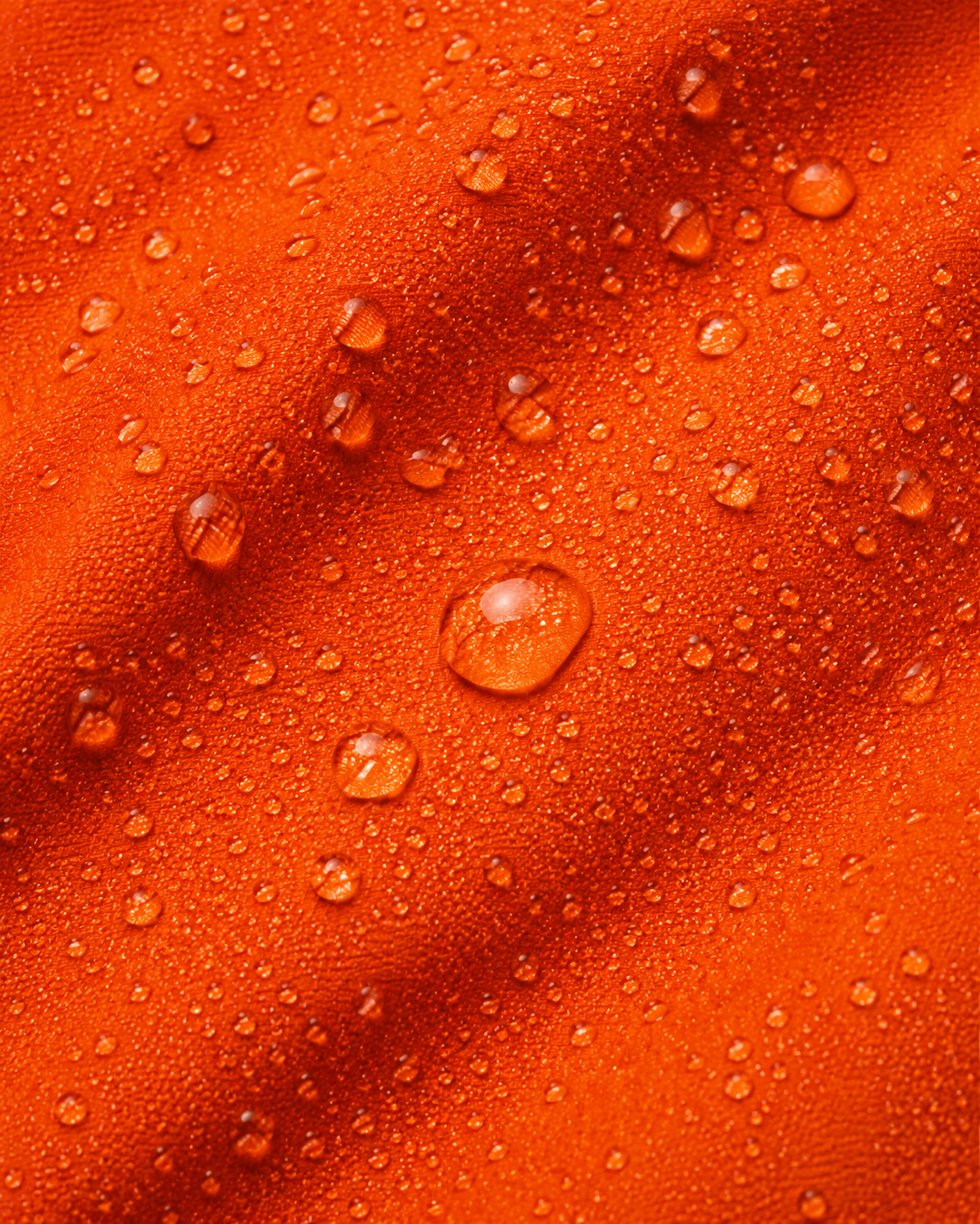 Water droplets beading on orange waterproof fabric