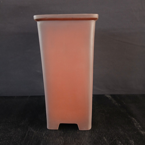 A front-facing, full-length view of a 6-inch tall unglazed cascade Yixing bonsai pot. The pot features a deep, rectangular shape with a subtle taper from the wide, flat rim at the top down to its base. It is crafted from traditional reddish-brown Yixing clay, giving it a smooth, earthy, and matte terracotta texture. The pot stands on four small, integrated feet formed by shallow arched cutouts on each side of the base. Set against a dark charcoal background on a black wooden-textured surface, the lighting highlights the pot's clean lines and warm color. This deep container is specifically designed for cascade-style bonsai trees, providing the necessary vertical space for their dramatic, downward-trailing branches.