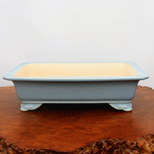 Light blue glazed rectangular pot on a polished reddish brown slab