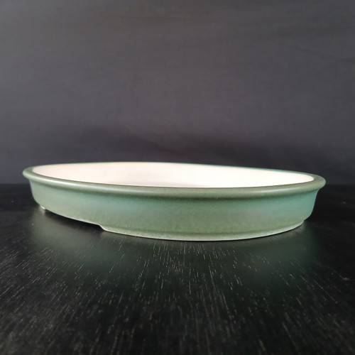 Shallow sea green oval pot with a white interior, seen edge on