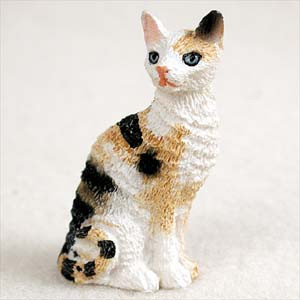 A detailed miniature figurine of a tortoise-white Cornish Rex cat, sitting upright with a curious expression. The hand-painted figurine features the breed's signature wavy fur texture, colored with patches of black, tan, and white. This charming calico cat ornament, with its bright blue eyes and pink nose, is designed as a decorative accessory for bonsai trees, terrariums, or miniature landscapes, adding a touch of personality and life to home decor.