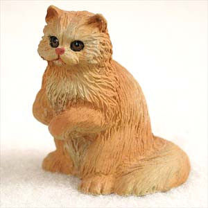 A detailed and realistic figurine of a long-haired red Persian cat, sitting in an attentive pose with its front paws gently tucked toward its chest and its head turned slightly to the right. The figurine features intricately textured, shaggy fur in shades of warm ginger and orange, with lighter creamy-tan highlights on the chest and around the distinctive flat face characteristic of the Persian breed. Its large, dark, glossy eyes and small pink nose add a charming, lifelike expression to the piece. The miniature cat sits upon a bed of fine white sand or decorative gravel against a plain background, illustrating its use as a whimsical accent piece for bonsai displays, fairy gardens, or home decor.