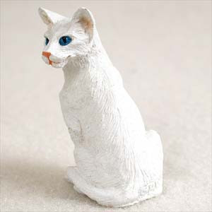 Miniature white Oriental Shorthair cat figurine seated upright, in three quarter view