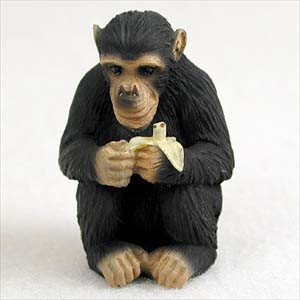 A detailed miniature chimpanzee bonsai tree figurine sitting in a squatting pose against a plain white background. The small animal figurine features realistic textures, with dark black fur and a wrinkled, light-tan face, hands, and feet. The chimpanzee is holding a partially peeled, off-white banana in both hands, looking forward with detailed dark eyes. This charming decorative accessory is designed to add a playful, natural touch to indoor bonsai tree displays or miniature fairy gardens.