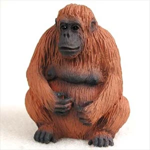 Miniature orangutan figurine seated, with a reddish orange textured coat