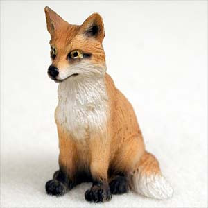 Miniature red fox figurine sitting alert, with orange red fur and a white chest