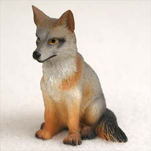 A detailed, hand-painted miniature gray fox figurine designed as a bonsai tree accessory. The fox is depicted sitting upright, featuring realistic textures and coloring, including a silvery-gray face with dark eye markings, a vibrant reddish-orange chest and front legs, and a bushy dark tail. This small decorative animal figurine is shown from a side-angle against a plain white background, highlighting its suitability for miniature landscapes, fairy gardens, and bonsai displays.
