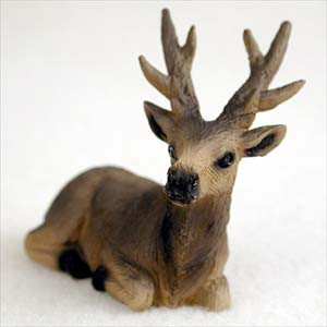 A small, detailed figurine of an elk bull lying in a resting position, designed as a decorative accessory for a bonsai tree or miniature garden. The figurine is crafted with realistic textures, featuring multi-pointed antlers and a coat of earthy brown shades that transition from light tan on the face and neck to a darker chocolate brown along the back. The elk's head is turned slightly toward the viewer, showcasing small, glossy black eyes and a prominent black nose. Its black hooves are tucked neatly beneath its body, and its ears are perked up. The figurine is set against a plain, soft-white background, highlighting its intricate design and suitability for adding a touch of wildlife to a natural bonsai landscape display.