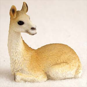 Miniature llama figurine resting, with a sandy tan body and a creamy white neck