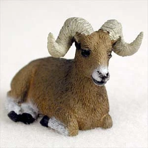 Miniature bighorn sheep ram figurine resting, with a brown and white coat