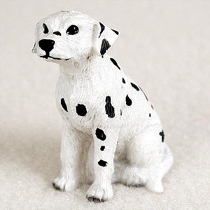 A small, detailed Dalmatian puppy figurine designed as a charming accessory for a bonsai tree or miniature garden arrangement. The miniature dog is depicted in a classic sitting pose, looking slightly to the left with alert, dark eyes and a prominent black nose. Its body is bright white and covered with characteristic irregular black spots scattered across its coat, floppy ears, and legs. The surface of the figurine has a subtle texture to mimic the appearance of short fur. This playful Dalmatian miniature from Bonsai Outlet adds a touch of life and whimsical character to indoor plant displays and landscaped bonsai scenes.