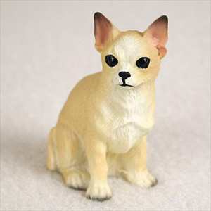 A detailed, miniature figurine of a tan and white Chihuahua dog, sitting in an upright pose against a neutral, soft-focus background. This small, lifelike pet ornament features large, round black eyes, a tiny black nose, and iconic pointed ears with dark brown tips. Its coat is painted with realistic fawn and cream tones, including a white chest and face with molded fur texture. Designed as a charming accessory for a bonsai tree display, this figurine adds a whimsical and personal touch to indoor miniature gardens and bonsai trays.