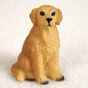 A detailed miniature figurine of a Golden Retriever dog, captured in a classic sitting pose. The figurine is crafted with a warm, golden-honey color and features realistic molded fur texture. It has an endearing facial expression with prominent black eyes, a black nose, and a simple black line for a mouth. Its characteristic floppy ears hang at its sides, and its front paws are finished with dark black accents at the toes. This charming Golden Retriever bonsai tree figurine is perfectly sized as a decorative accent for penjing or indoor bonsai displays, adding a touch of personality and warmth to the miniature landscape. The figurine sits against a soft, white textured background, highlighting its rich color and fine details.