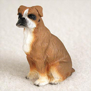 A detailed miniature figurine of a Boxer dog with natural, uncropped ears, intended as a decorative accessory for a bonsai tree or miniature garden. The fawn-colored dog is depicted in a sitting position, looking slightly towards the left with a calm expression. It features realistic sculpted fur textures and classic breed markings, including a black mask around the muzzle, a white blaze on its face, a white chest, and white markings on its paws resembling socks. Its uncropped ears hang naturally down the sides of its head. The figurine is set against a plain, light-colored background, highlighting its compact and muscular build.