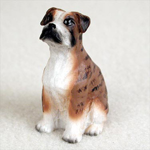 A detailed, hand-painted miniature Boxer dog figurine, specifically designed as an accessory for bonsai trees or fairy gardens. The figurine depicts a brindle Boxer with uncropped, floppy ears, sitting in a patient pose and looking slightly upward. Its coat is a warm tan color with dark brown brindle stripes, accented by a white chest, white muzzle, and white paws. The face features realistic black markings around the muzzle and eyes. The figurine is shown from a three-quarter view against a plain, off-white background, highlighting the craftsmanship and lifelike expression of the dog.