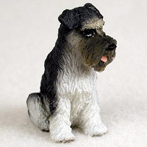 A detailed miniature figurine of a gray and white Schnauzer dog, designed as a decorative accessory for a bonsai tree display. The figurine shows the dog in a sitting pose, looking off to the side with its small pink tongue slightly visible. It features the characteristic salt-and-pepper coat of the breed, with darker gray on the back, snout, and uncropped ears, and lighter white fur on its chest and legs. The figurine's surface is finely textured to mimic the wiry coat of a real Schnauzer dog.