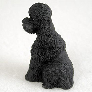 Miniature black poodle figurine with a sport cut, shown from a rear three quarter view